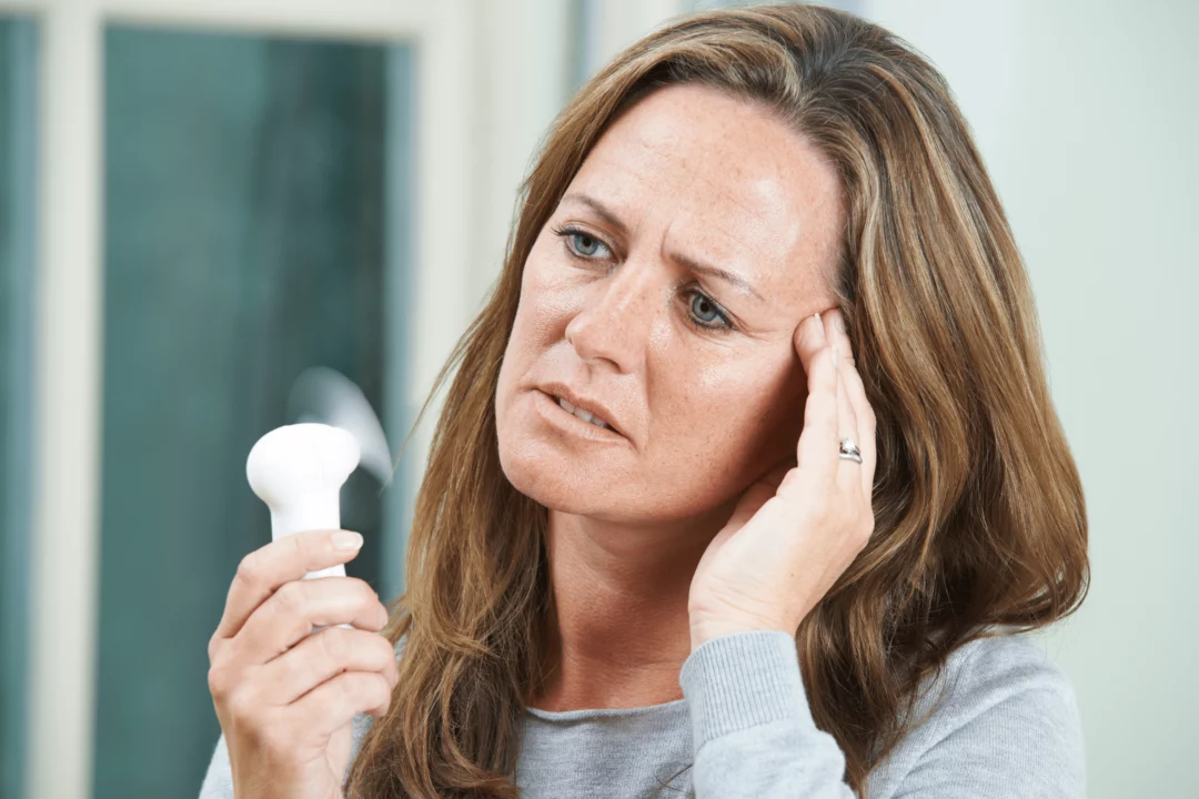 zena se snazi ochladit ventilatorem behem horkeho dne kdyz trpi navaly horka priznaky menopauzy a reseni
