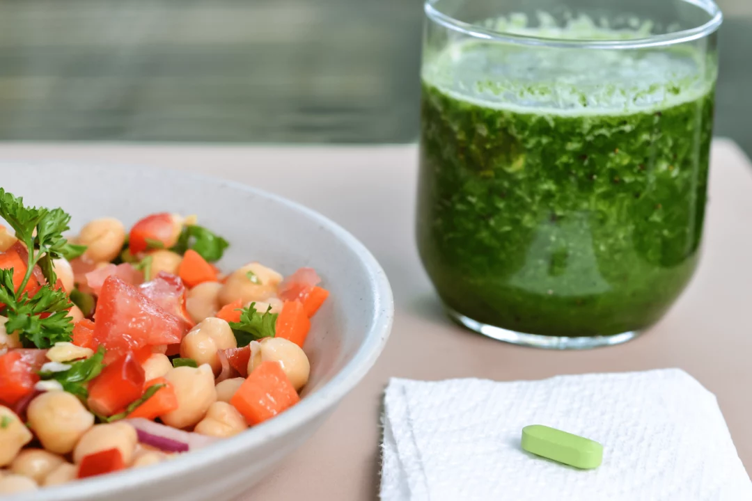 cerstvy cizrnovy salat s rajcaty v mise zelene smoothie ve sklenici a doplnek stravy na ubrousku zdrava svacinka