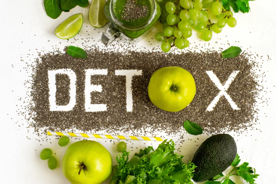 Chia semínka tvoří slovo DETOX mezi čerstvou zeleninou, jablky a hroznovým vínem na bílém pozadí.