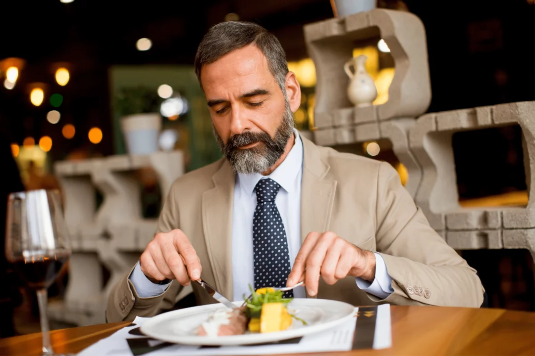 muz v obleku ji elegantni jidlo v restauraci na stole sklenice vina zatisi s dekorem v pozadi