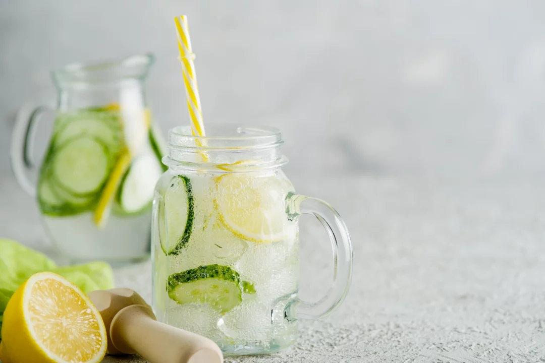 sklenice osvezujici okurkove limonady s citronem a ledem letni napoj na bilem pozadi zlute brcko